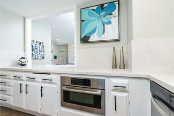 a kitchen with white cabinets and a painting on the wall